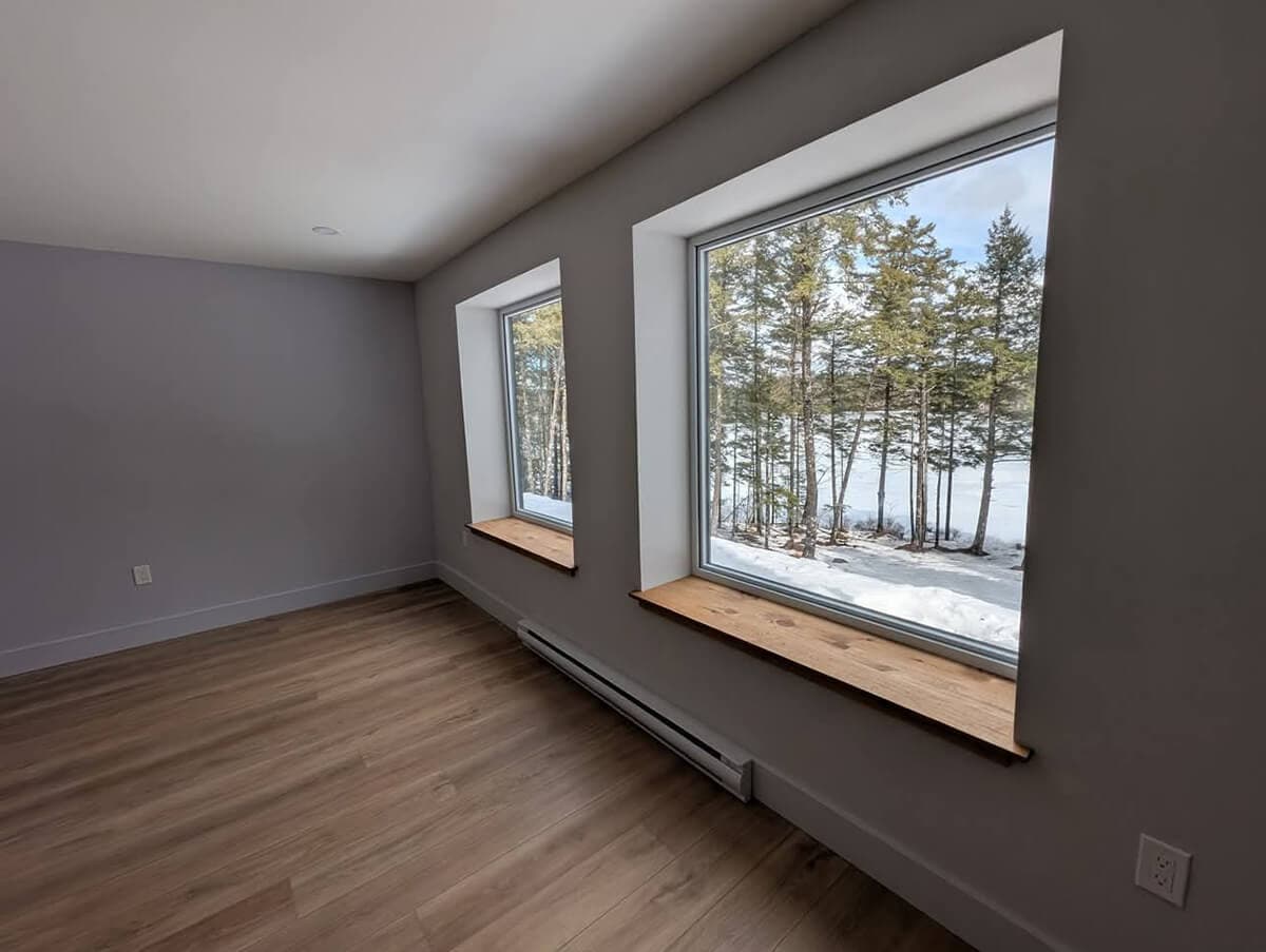 Interior finish of a bedroom, with two windows facing a snowy backyard