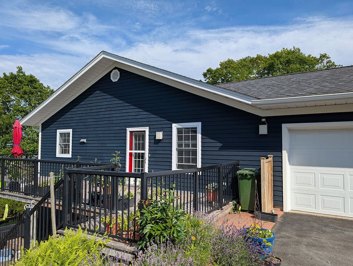 The exterior view of a freshly painted dark blue house with a deck on a sunny day